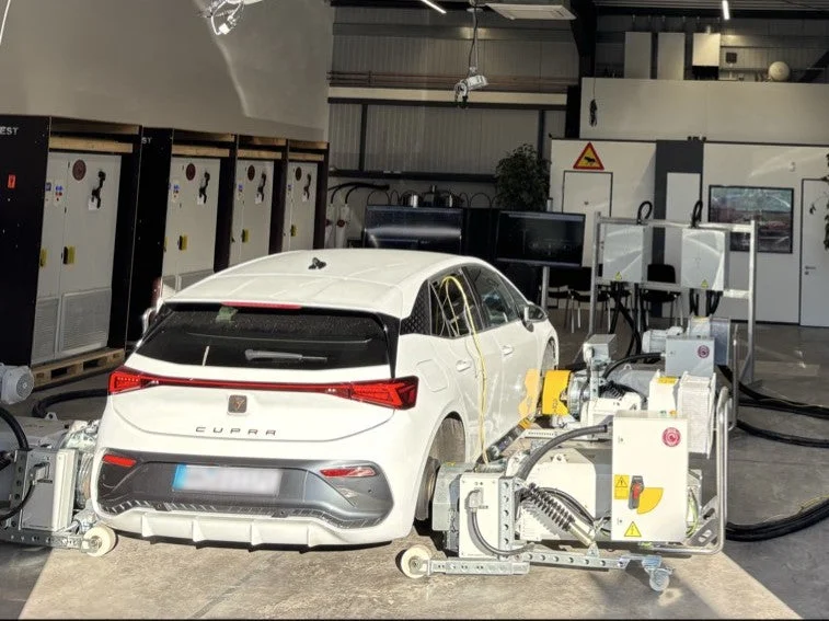 試験施設内で機器に接続されている白いクーペスタイルの車