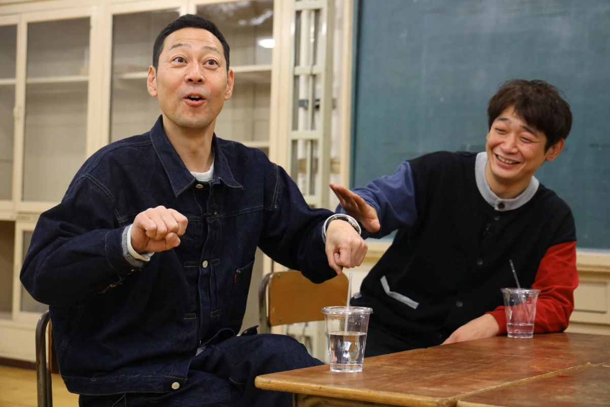 デスクで笑顔で会話する男性2人