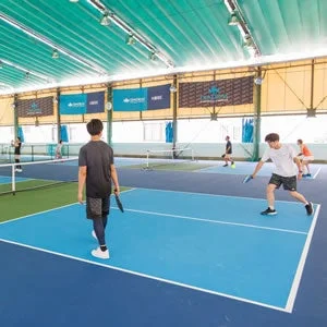 屋内コートで複数の人々がピクルボールを楽しむ様子