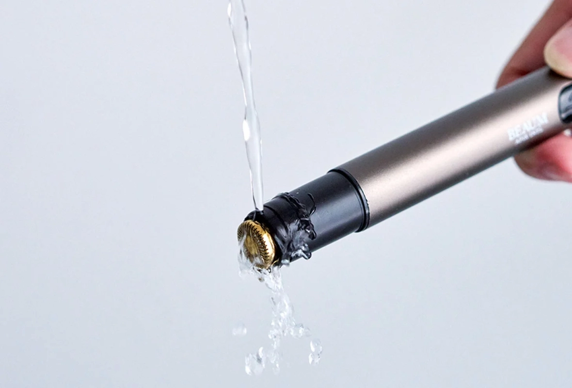 手で持った細身の電動シェーバーに水がかけられている様子