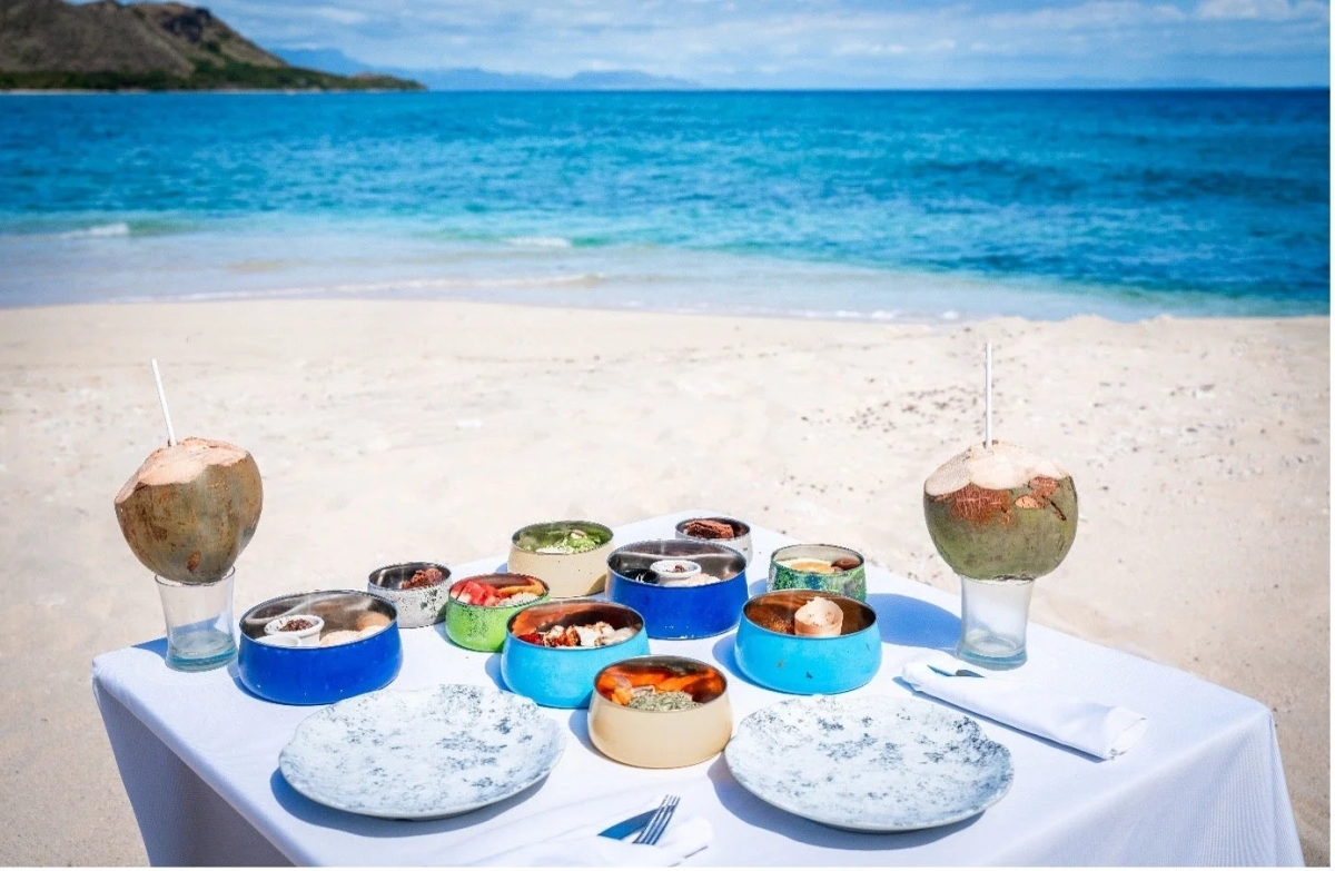 白い砂浜のビーチに置かれたテーブルで食事を楽しむ様子