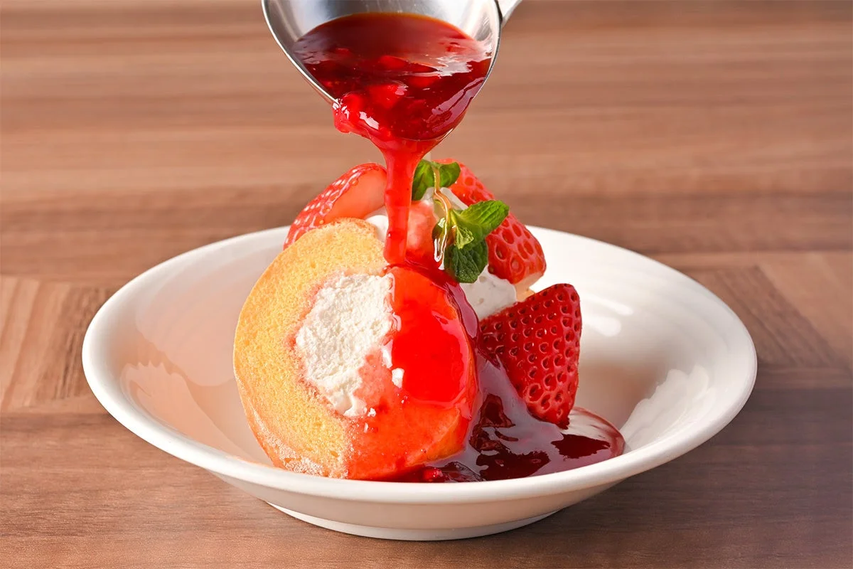 いちごとストロベリーソースがかけられたロールケーキ