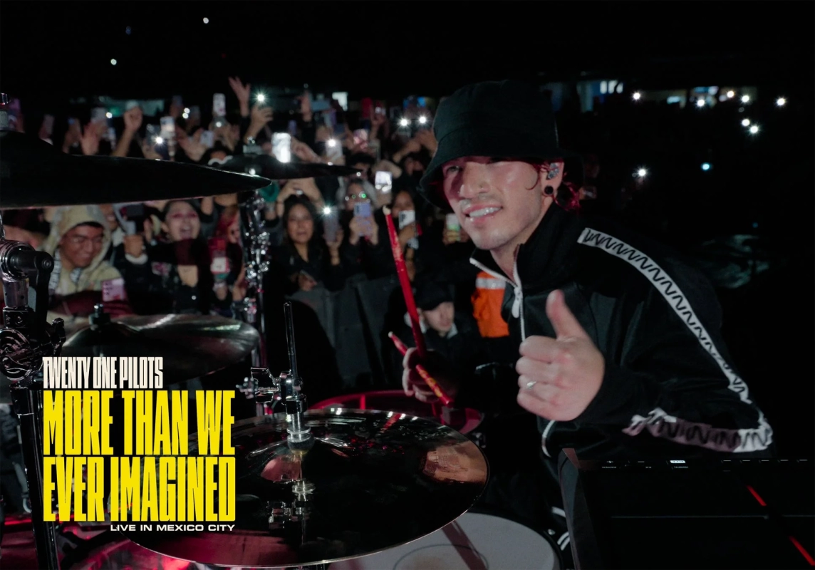 人気バンド「Twenty One Pilots」のドラマーがメキシコシティでのライブ中にドラムを演奏し、観客にサムズアップしている写真