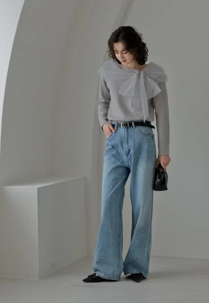 グレーのトップスに大きなリボンがあしらわれ、パール装飾のワイドデニムを合わせた女性の全身コーディネート。黒い小物で引き締めた、上品さとカジュアルさを兼ね備えたスタイリングです。