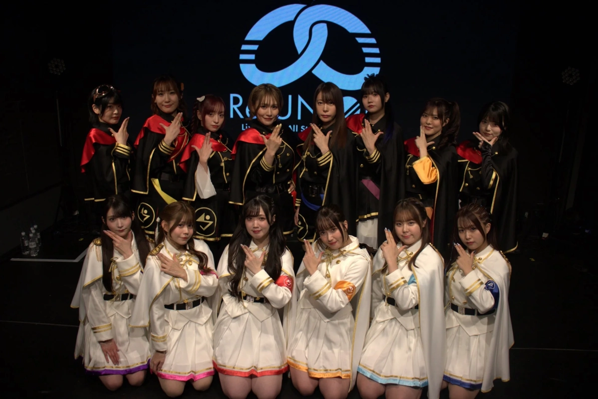 ステージ上でポーズをとるアイドルグループの集合写真