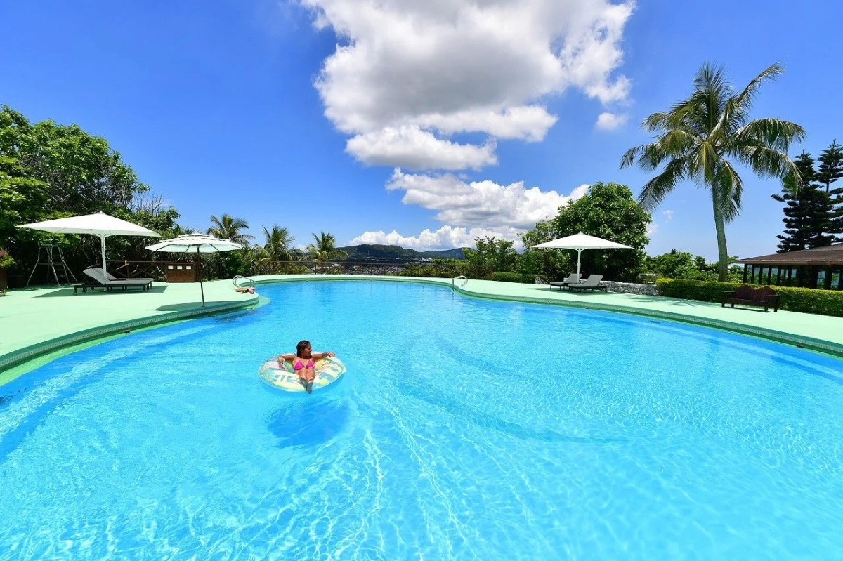 プールで浮き輪に乗りリラックスする女性